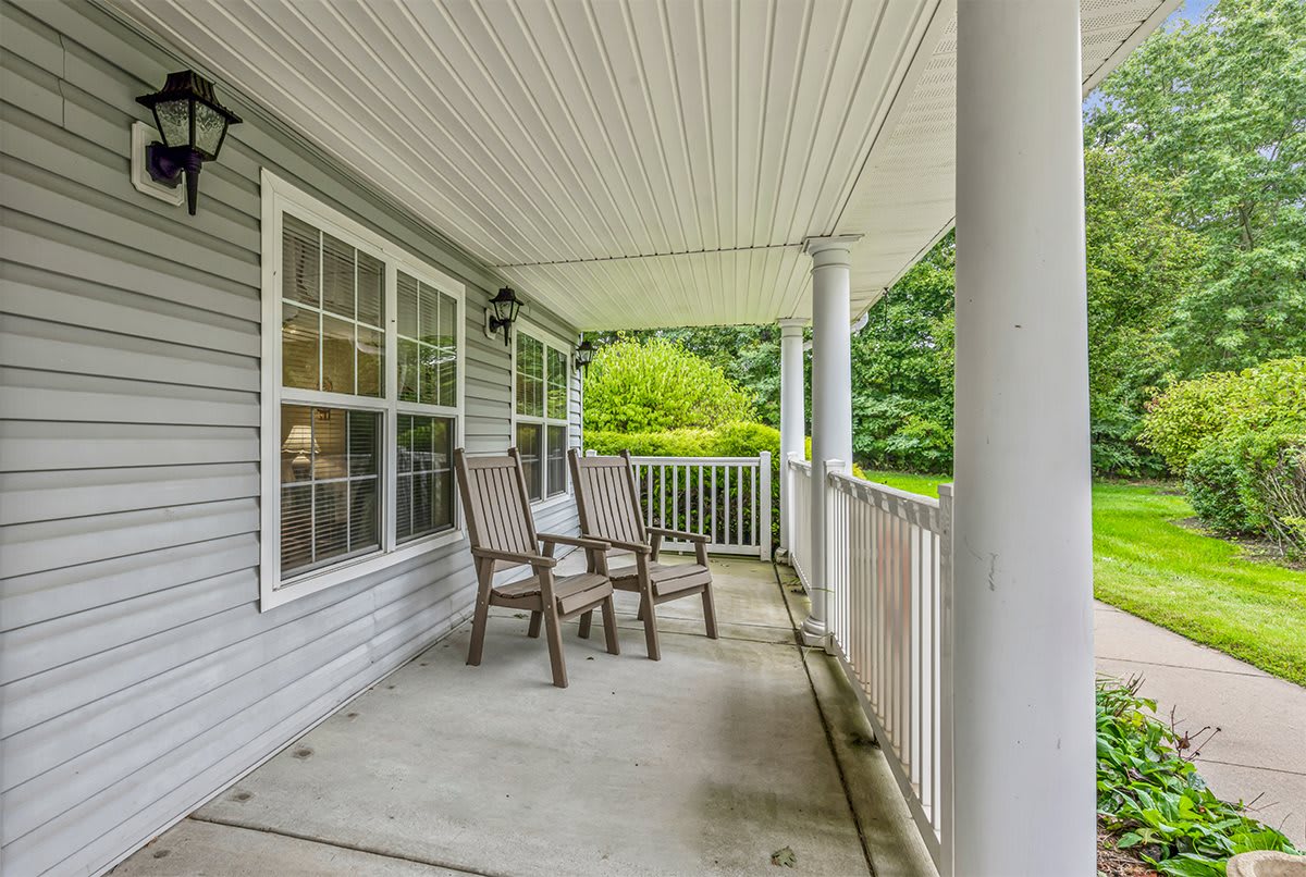 A cozy porch with two chairs overlooking a garden.