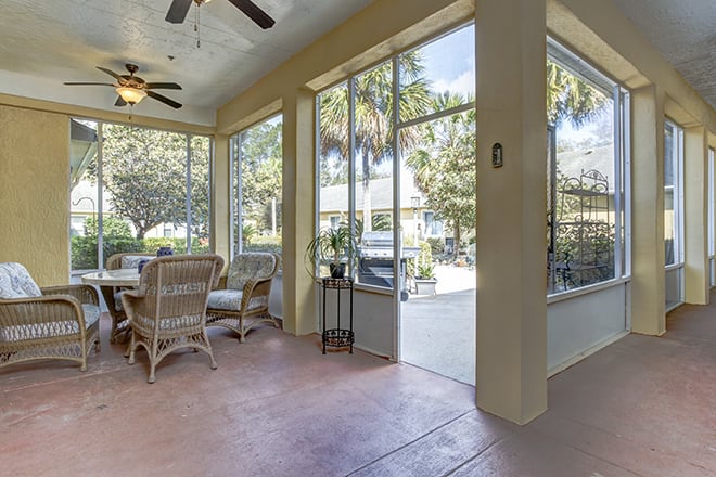 A bright sunroom featuring wicker furniture, large glass windows, and ample natural light.