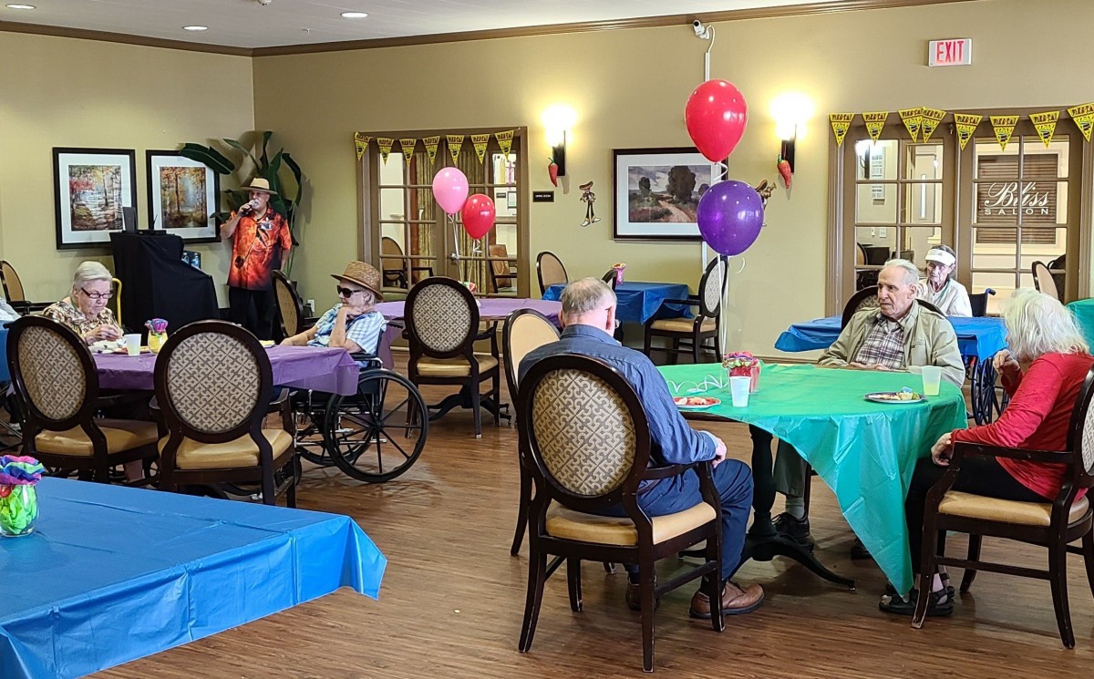 A community gathering with decorations, including colorful balloons and tables in a warm indoor setting.