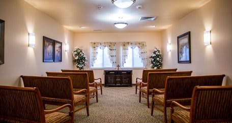 A small chapel interior with seating and decorative plants.