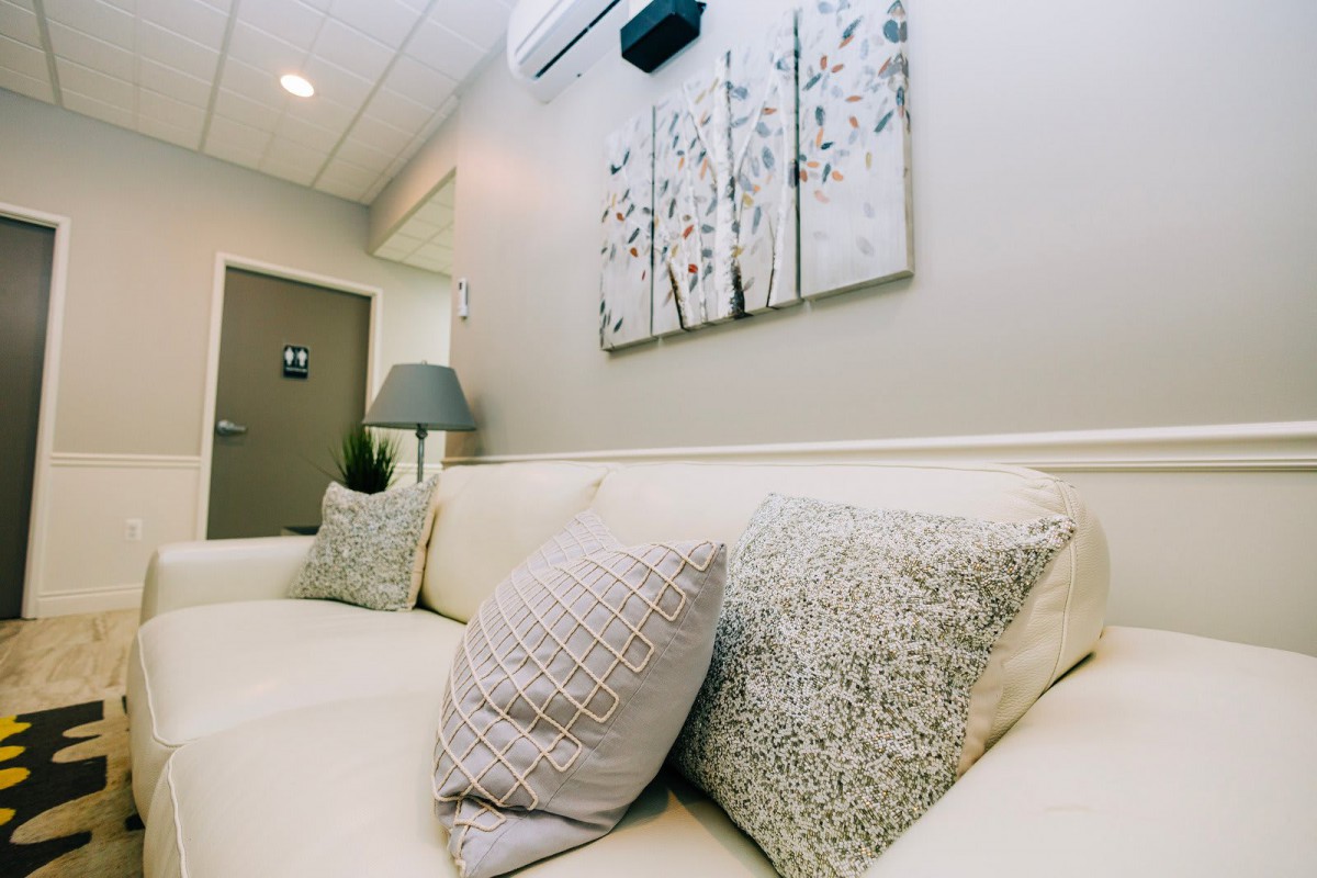 A cozy living room with a comfortable sofa adorned with cushions and a decorative painting on the wall.