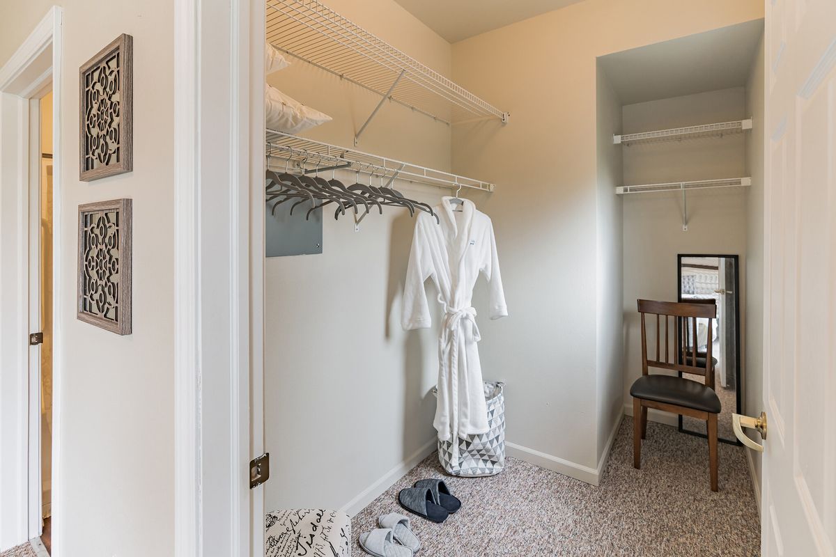 A neatly organized closet with a robe hanging and some clothing items on the floor.