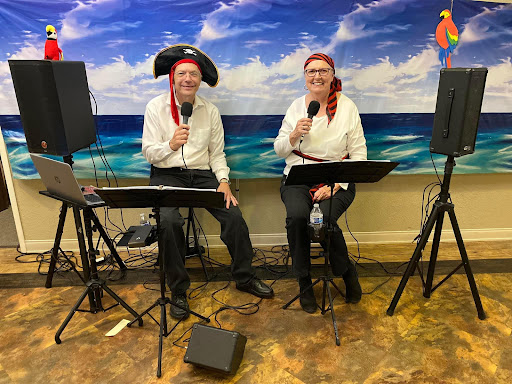 A lively pirate-themed musical performance by a duo in front of a beach backdrop.