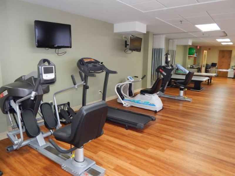 A well-equipped gym featuring treadmills and stationary bikes on a wooden floor.