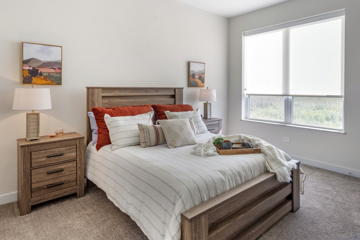 A modern bedroom with wooden furnishings and a cozy atmosphere, filled with natural light.
