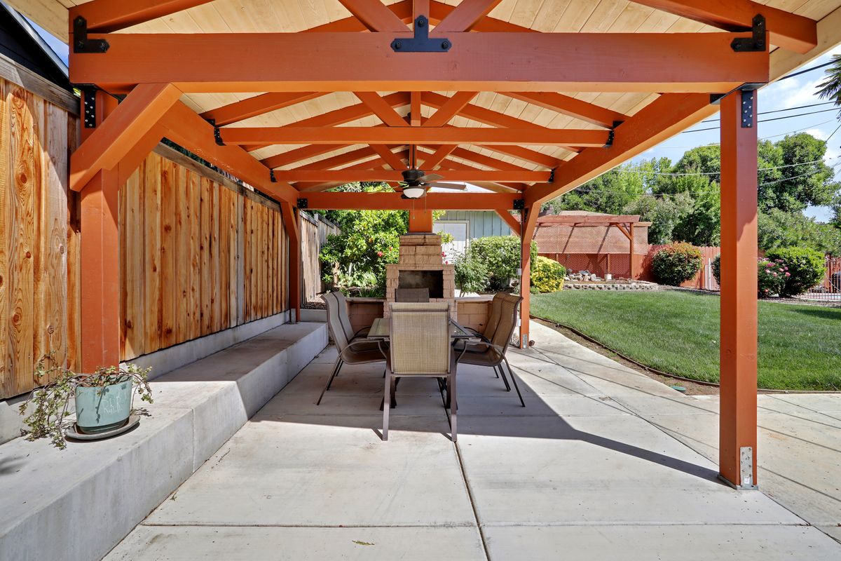 A backyard patio with a pergola, furnished with a table and chairs for outdoor dining.