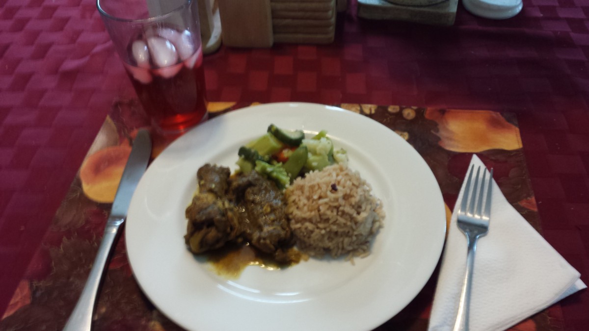 A delicious meal featuring rice, meat, and vegetables, served with a chilled drink.