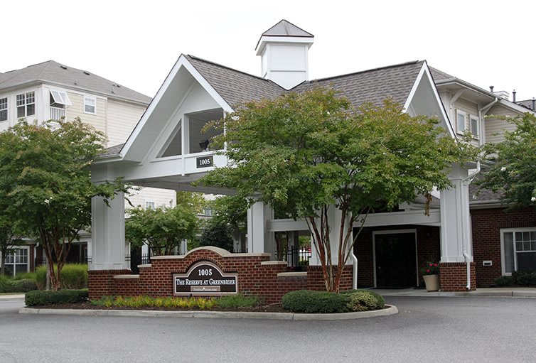 A hotel entrance with a landscaped garden and trees.