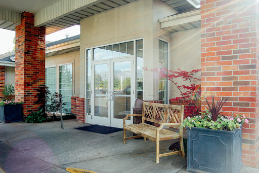 A welcoming entrance with a wooden bench and vibrant plants.