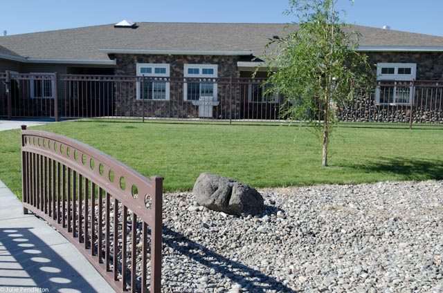 A house with a landscaped yard featuring grass, a tree, and decorative rocks.