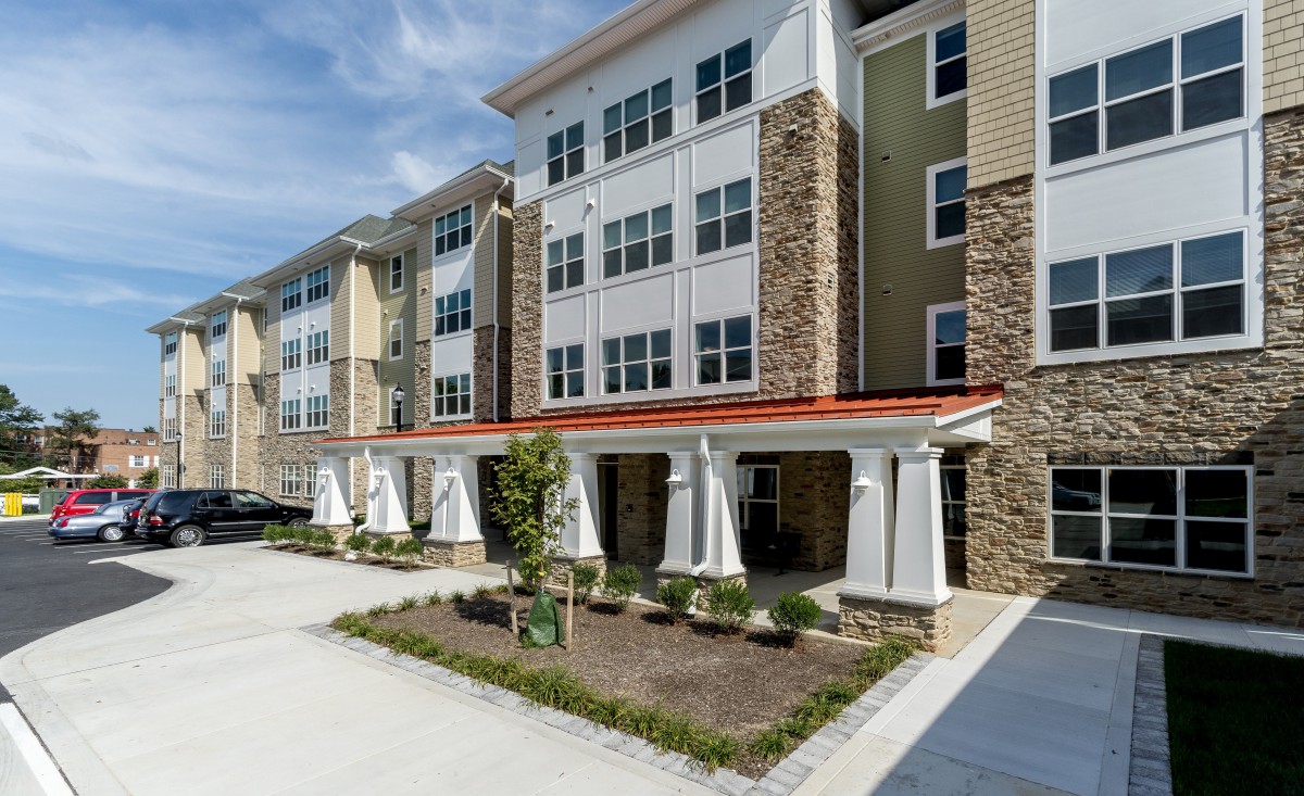 A modern multi-story apartment building with a brick and siding exterior.