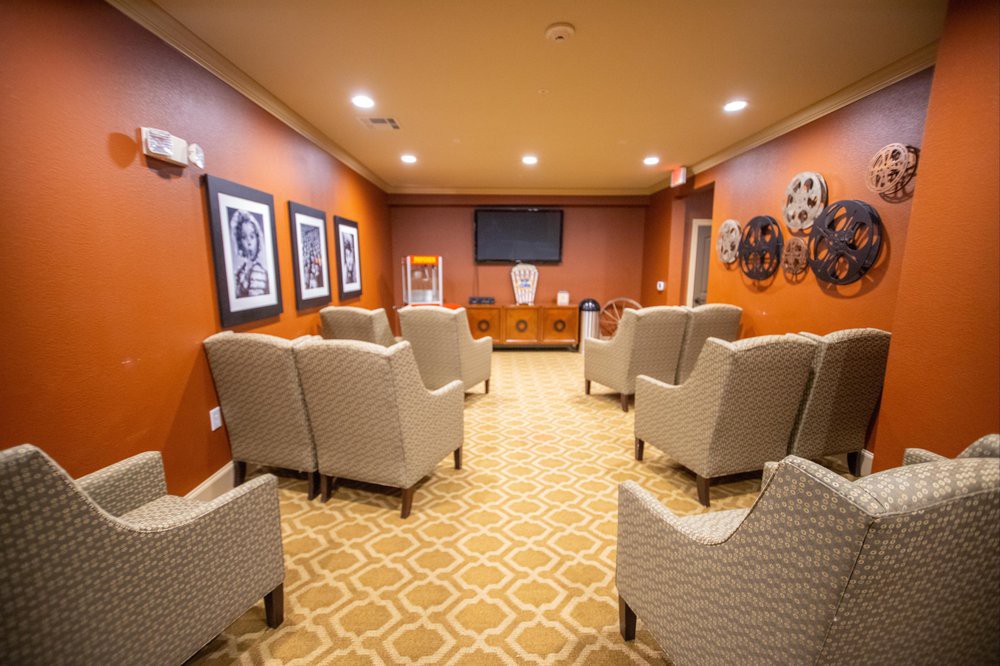 A cozy lounge area with comfortable chairs and a television, adorned with wall art and a patterned carpet.