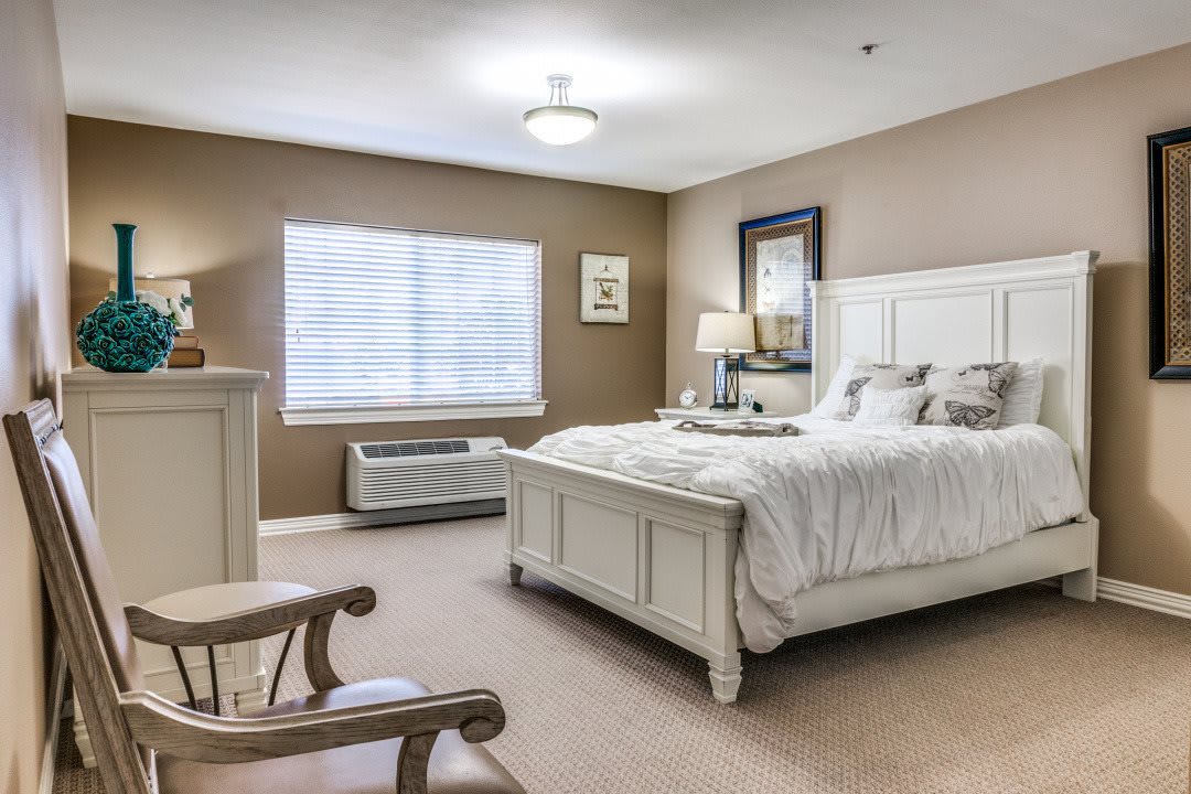 A cozy and elegantly furnished bedroom with a large bed, soft carpeting, and ample natural light.