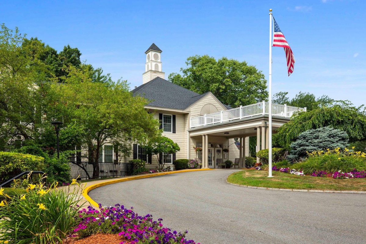 A welcoming building with an American flag, surrounded by lush landscaping and vibrant flowers.
