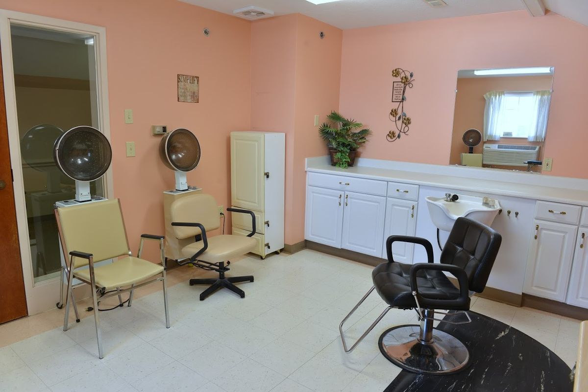 A cozy hair salon with pink walls, featuring chairs and hair dryers.