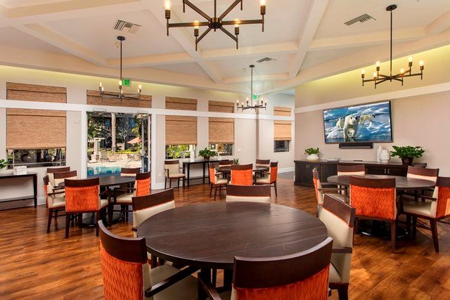 A modern dining area with circular tables, upholstered chairs, and elegant lighting.