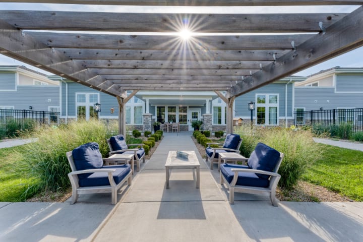 A stylish outdoor seating area featuring a pergola with comfortable patio furniture under the bright sun.