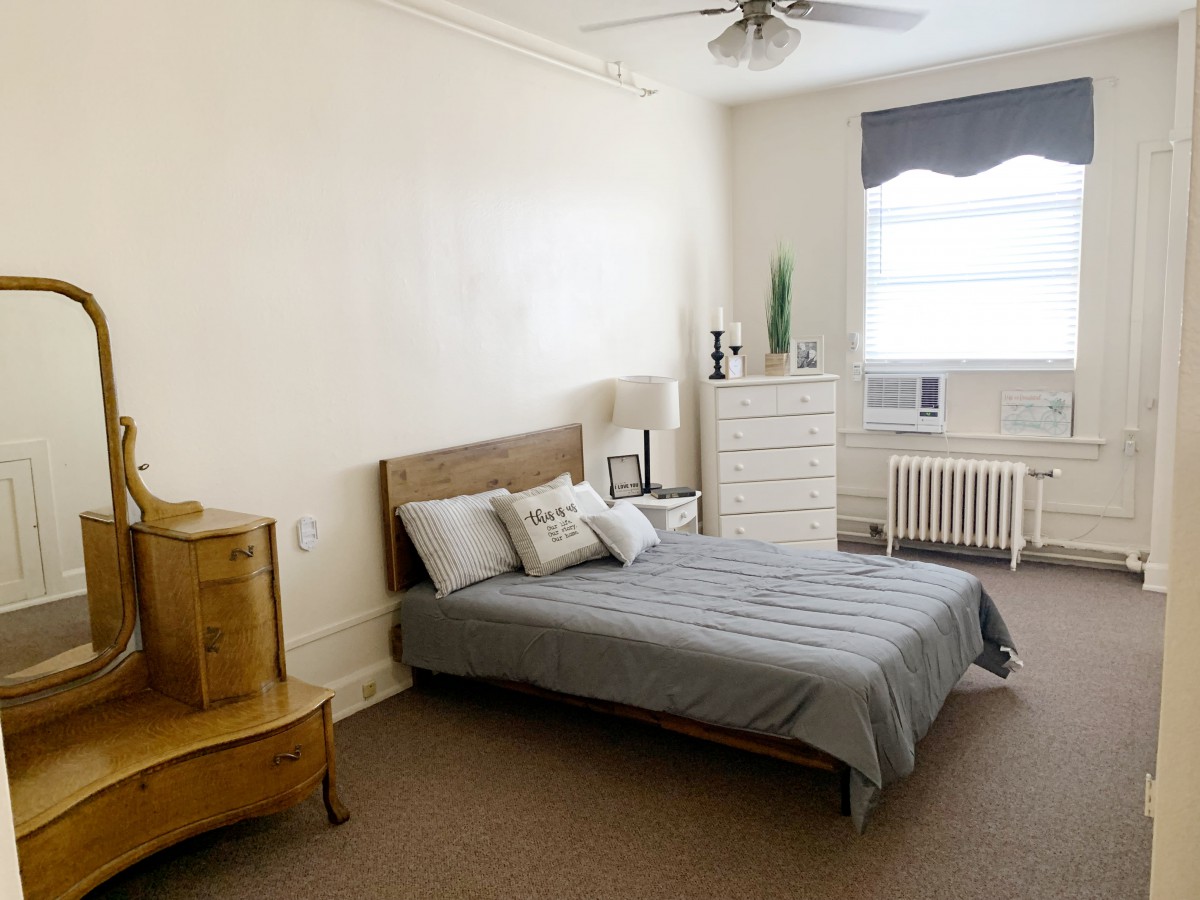 A minimalist bedroom with a bed, dresser, and window.