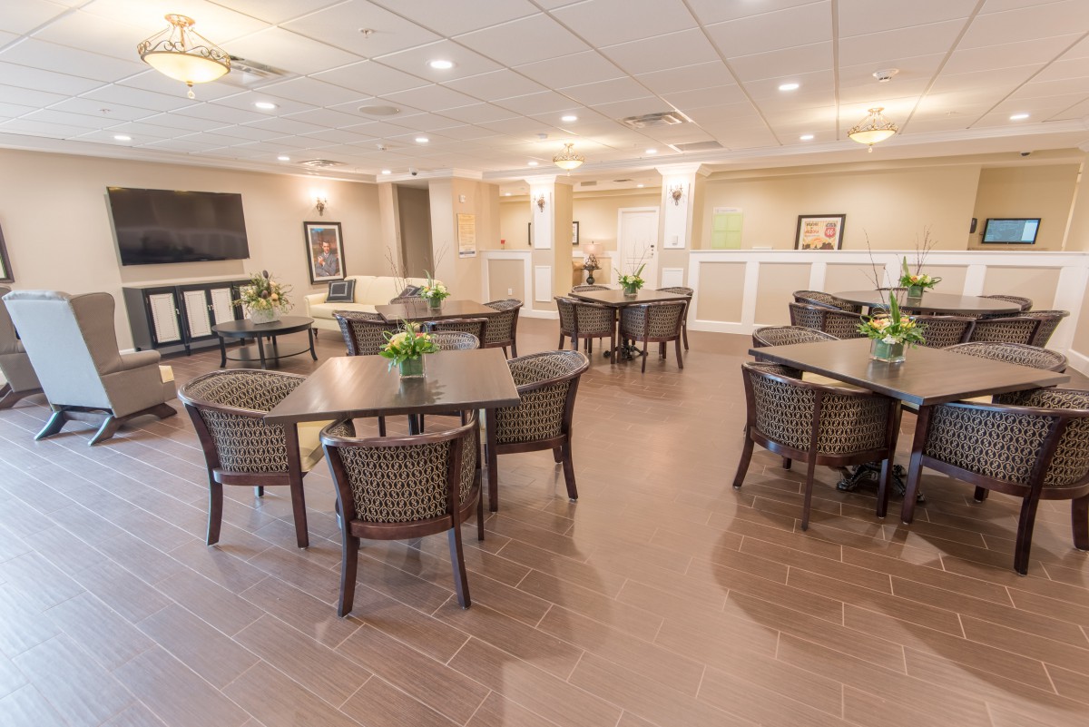 A spacious and well-lit dining area with neatly arranged tables and chairs, adorned with decorative plants.