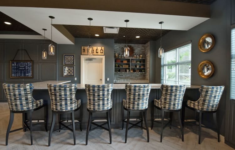 A modern home bar with plaid stools and pendant lighting.