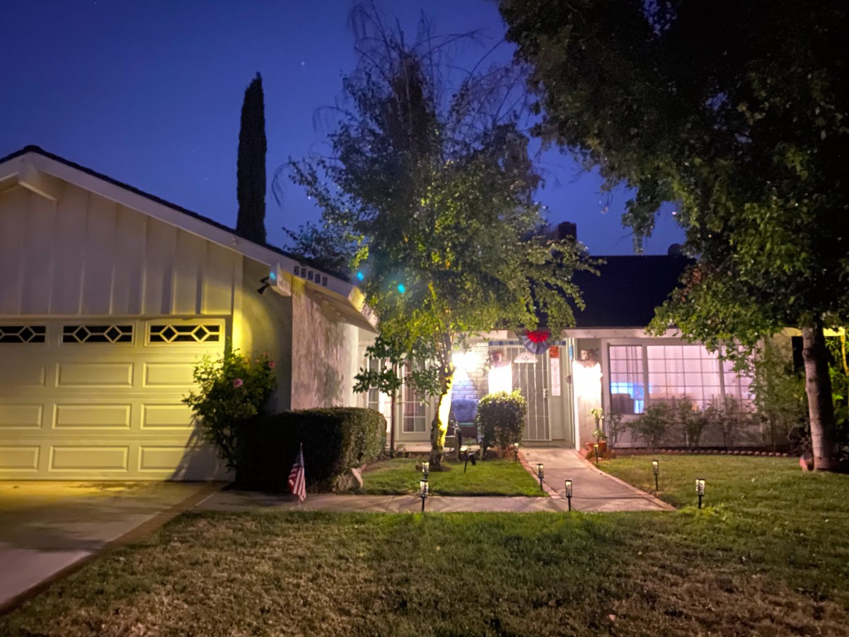 A cozy house illuminated at night with a well-lit pathway leading to the entrance.