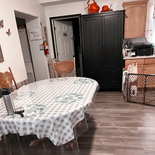 A cozy kitchen dining area featuring a checkered tablecloth and warm wooden furnishings.