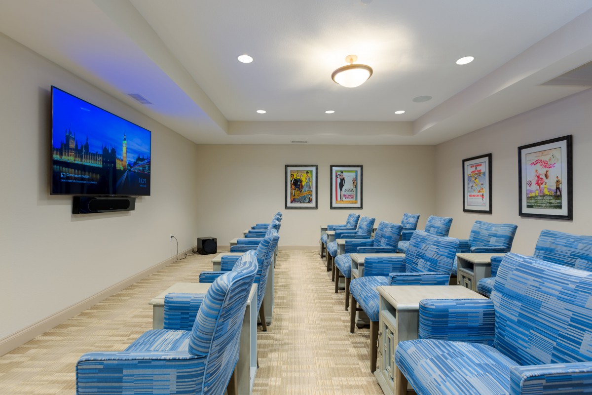 A cozy theater room with blue seating and a large screen.