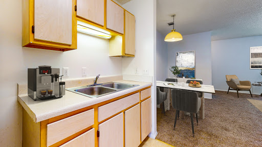 A cozy kitchen with wooden cabinets, equipped with a sink and adjacent dining area.