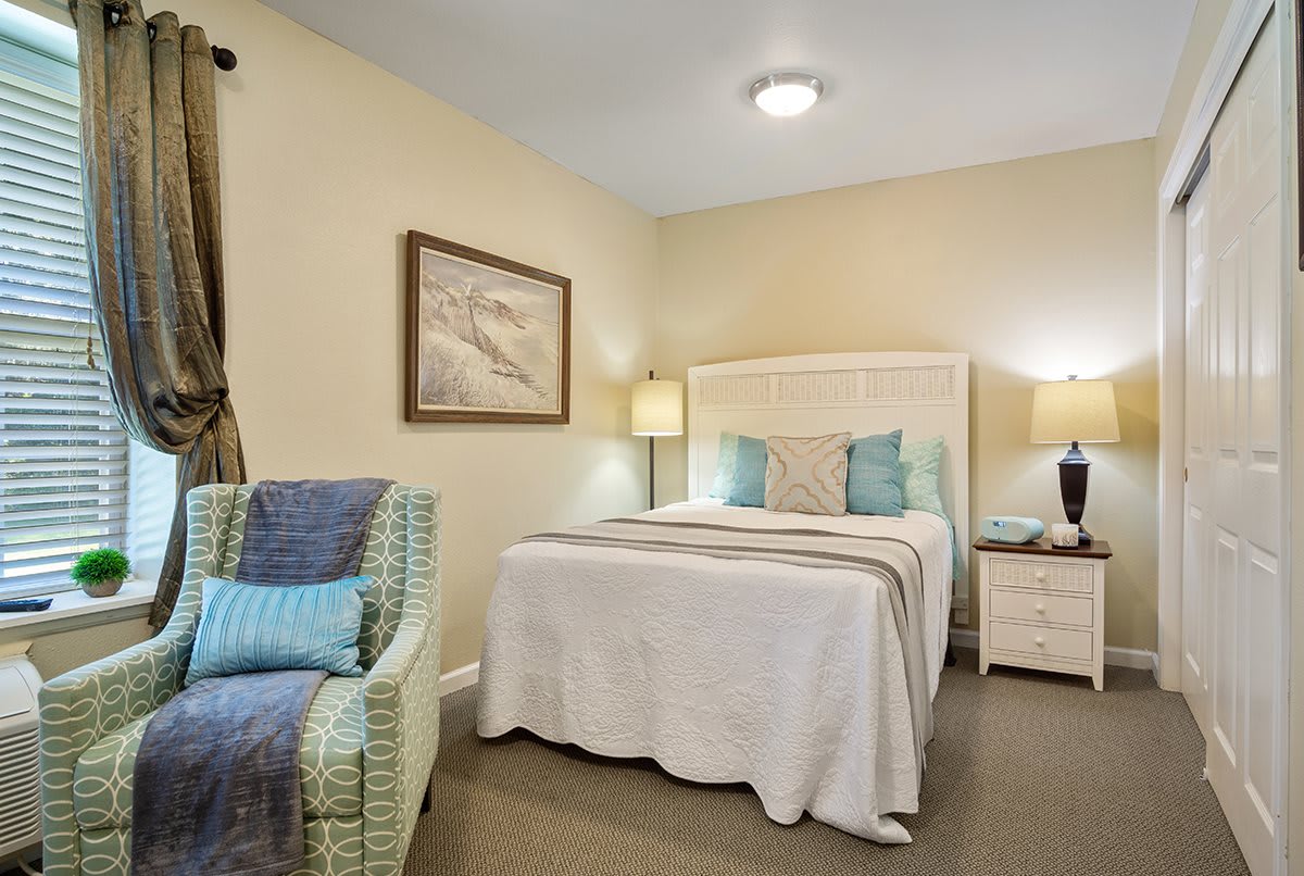 A cozy bedroom with a comfortable bed, nightstands, and an armchair.