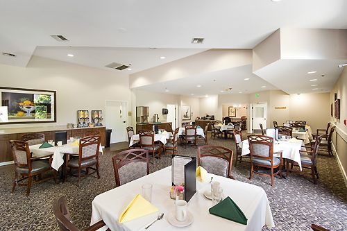 A well-lit dining room with multiple tables and chairs, set up for guests.