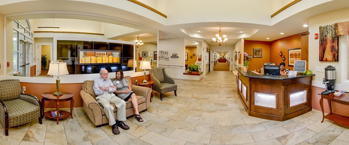 A spacious lobby with seating area and reception desk, featuring chandeliers and decor.