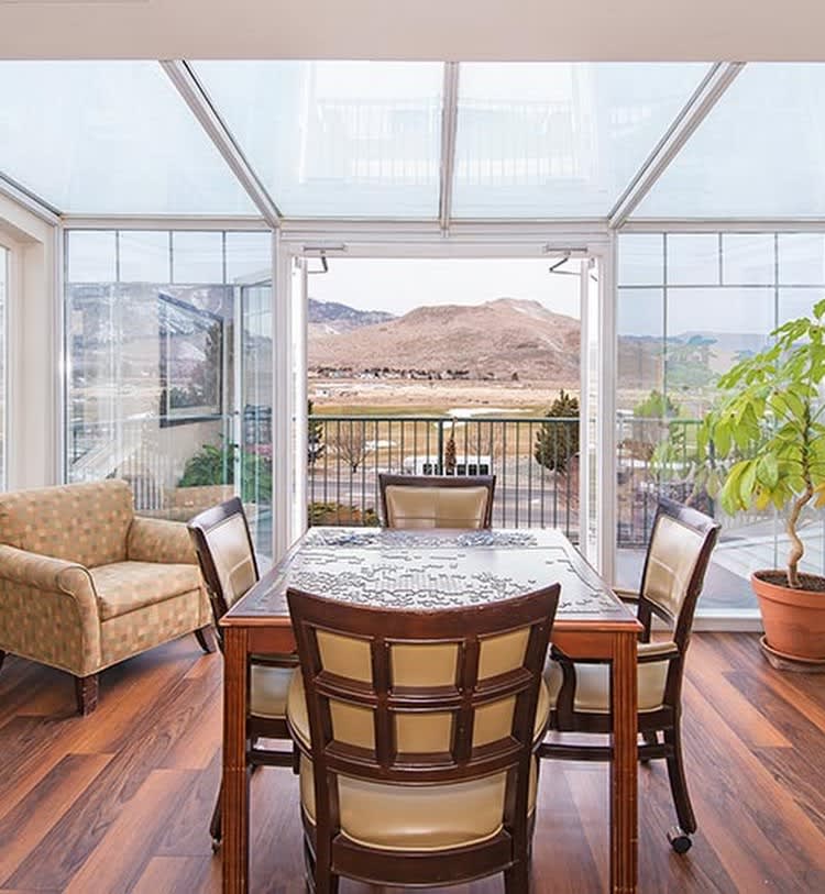 Bright sunroom with a dining set and indoor plants overlooking a scenic outdoor view.