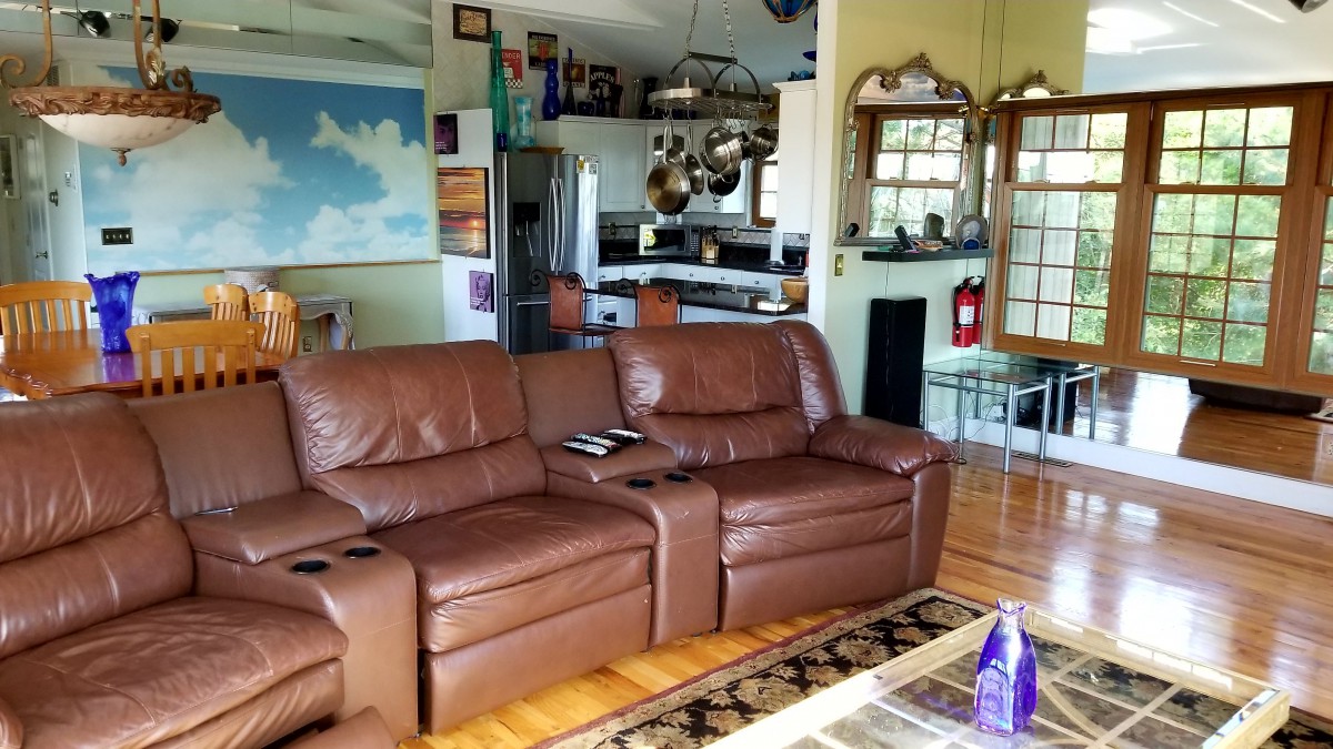 A cozy living room with a brown leather sofa and an open view of the kitchen area.