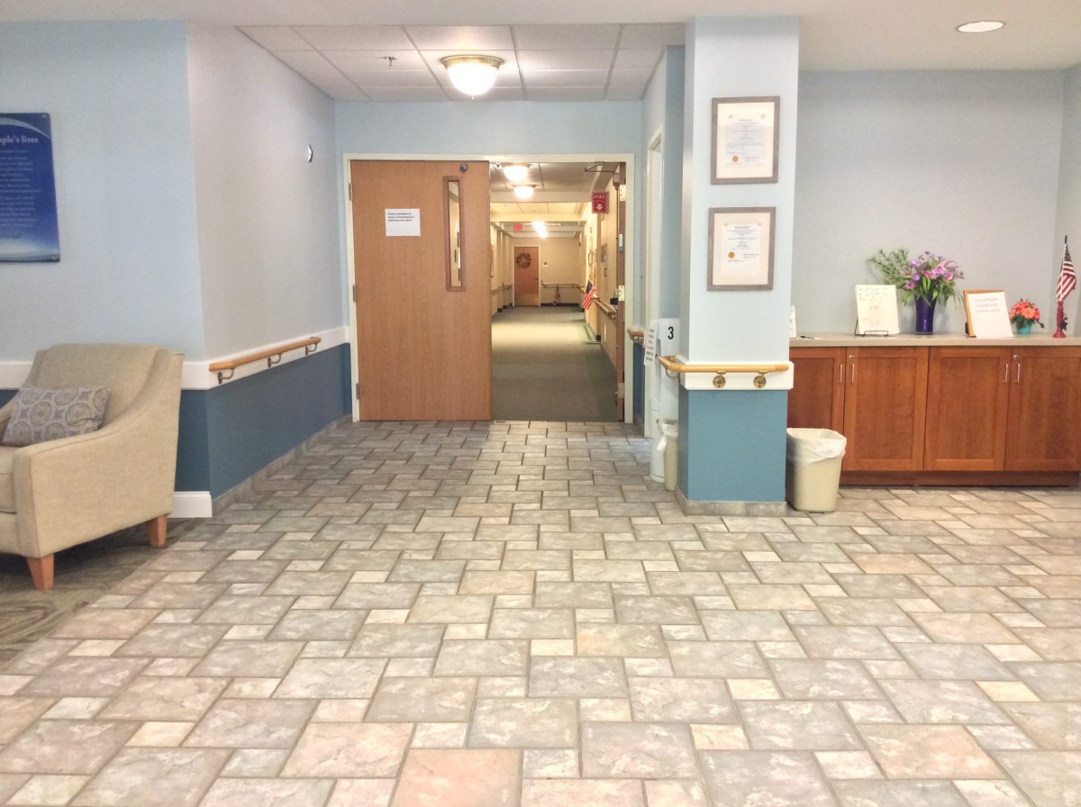 A tiled hallway interior with a closed wooden door and decorative furniture.