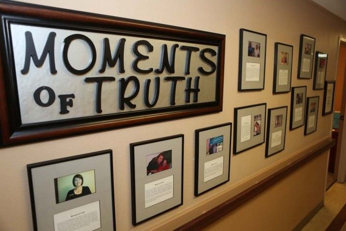 A hallway wall displaying framed photos and text under the title 'Moments of Truth'.