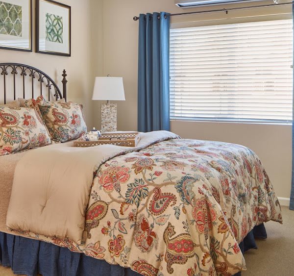A cozy bedroom with floral bedding and blue curtains.