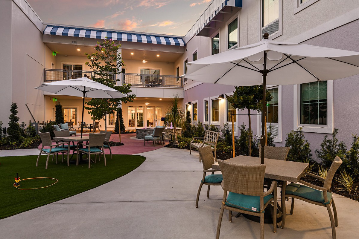 A beautifully landscaped courtyard featuring outdoor seating with umbrellas in the evening.