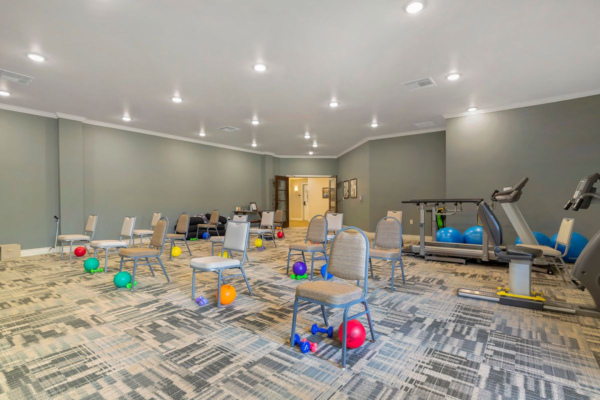 A spacious exercise room with chairs and fitness balls arranged on a carpeted floor.
