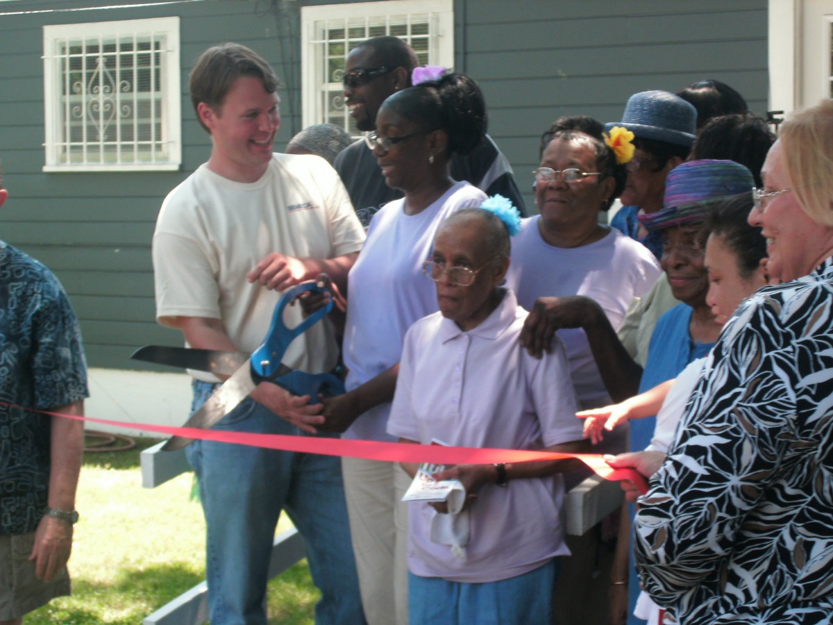 A group of people gather for a ribbon cutting ceremony at a community event.