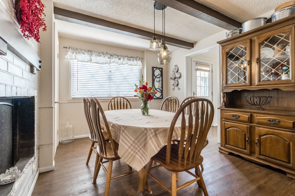 A cozy dining room with a wooden table set and a vase of flowers in the center.