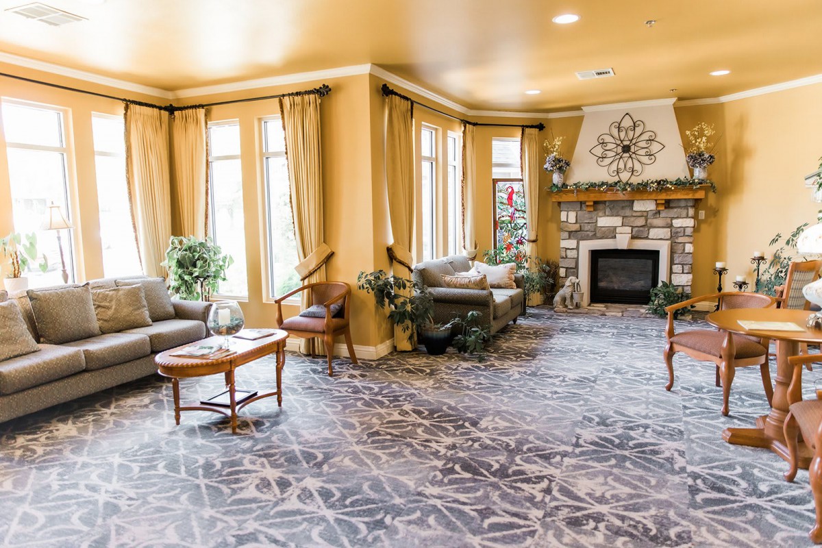 A cozy living room with a fireplace, sofas, and large windows.