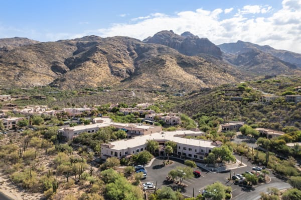 A scenic view of buildings nestled in a desert landscape with mountains in the background.