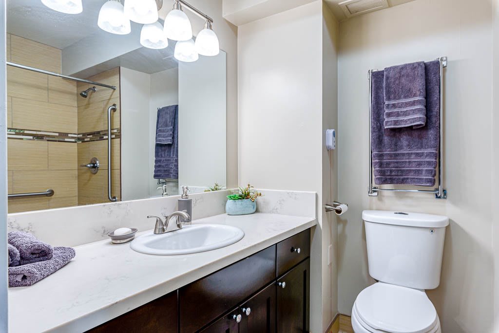 A modern bathroom with a sink, mirror, and neatly arranged towels.