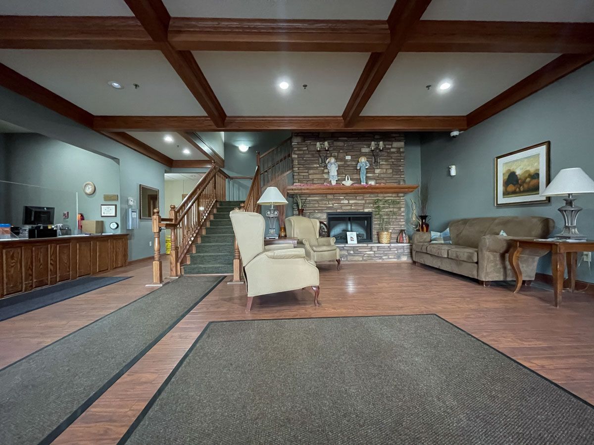 A welcoming lobby with comfortable seating, a fireplace, and wooden stairs leading to the upper floor.