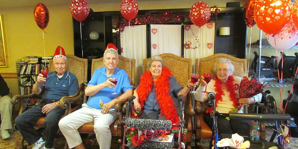 Elderly friends enjoying a festive celebration with balloons and drinks.