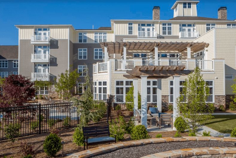 A modern residential apartment complex with landscaped gardens and outdoor seating areas.