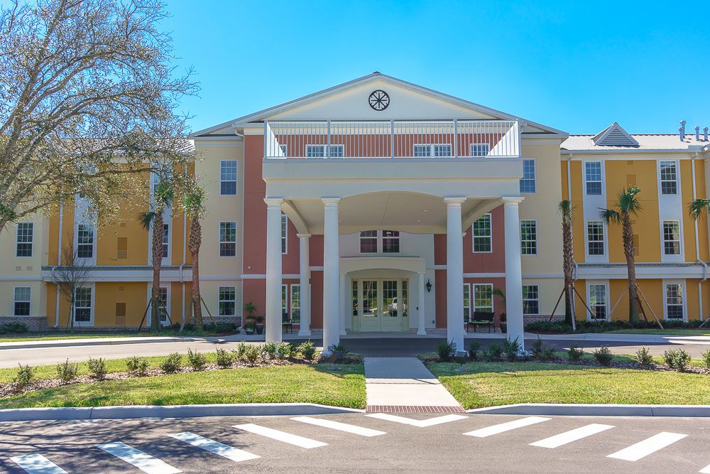 A residential building with a grand entrance featuring columns and landscaped surroundings.