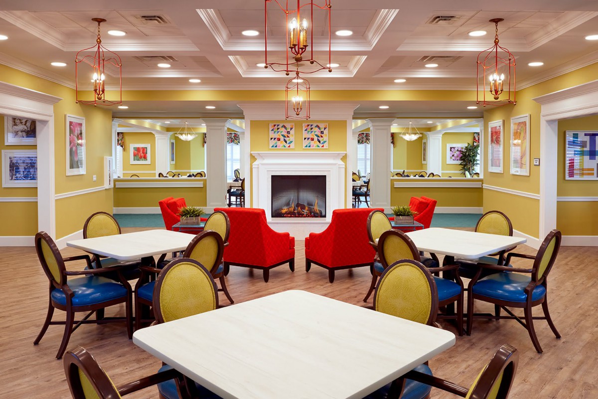 A vibrant seating area with colorful furniture, featuring a central fireplace and elegant lighting.