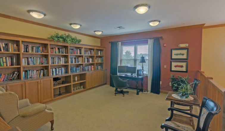 A cozy library room with bookshelves, a desk, and a window.