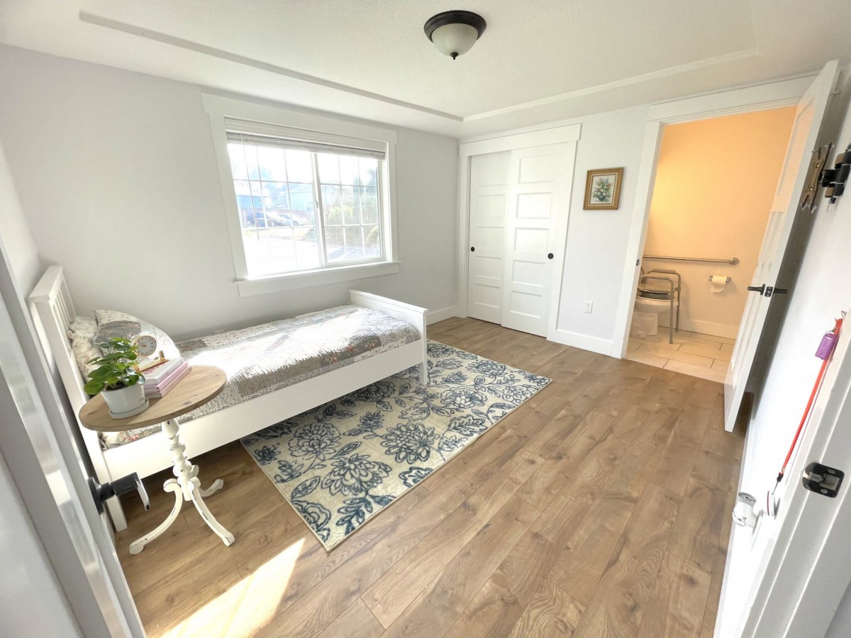 Bright bedroom with a daybed, hardwood floors, and a decorative rug.